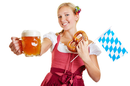 Happy woman in a dirndl holding beer, pretzel and a bavarian flagの写真素材