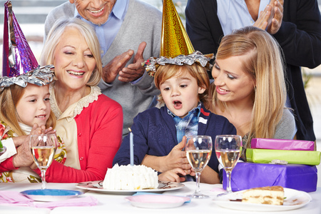 Happy boy celebrating birthday with his family and his grandparentsの写真素材