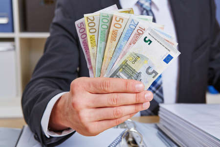 Hand of a business man in the office holding Euro money billsの写真素材
