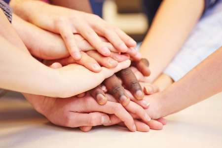 Motivation and teamwork with many hands stacked in school