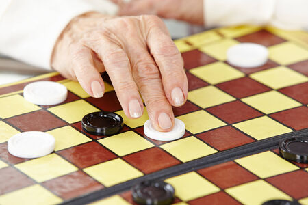 Wrinkly hand of a senior woman playing checkersの写真素材