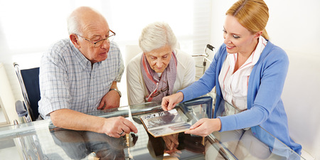 Senior citizens couple watching a photo album with their daughter
