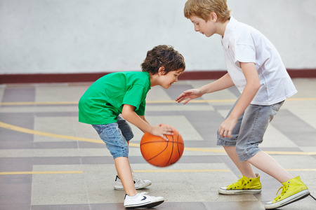 Two boys playing basketball together in the schoolyard of a schoolの写真素材