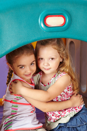 Two befriended girls embracing in a kindergartenの写真素材