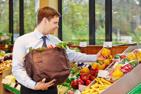 Smiling businessman buying fresh vegetables in an organic food storeの写真素材