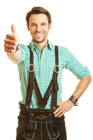 Happy bavarian man in leather pants holds his thumbs upの写真素材