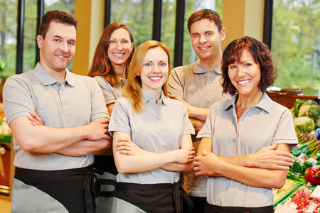 Happy team of smiling men and women staff in a supermarketの写真素材