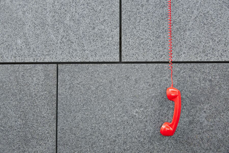 Red emercency call phone hanging down on a wallの写真素材