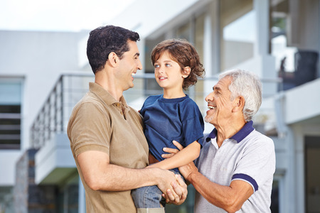 Happy men in three generations of a family in front of a house