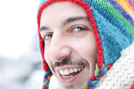 Happy young man smiling in winter with a colorful wool capの写真素材