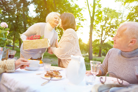 Senior woman bringing gift to birthday party in a summer gardenの写真素材