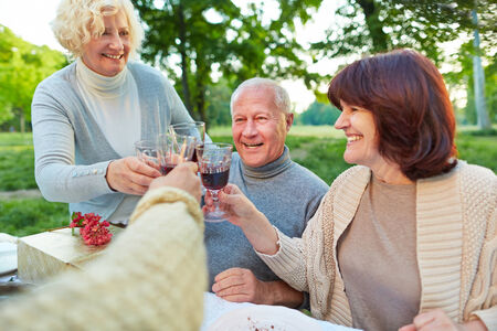 Happy senior friends cheering with glass of red wine at birthday partyの写真素材
