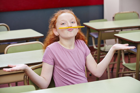 Girl doing nonsense in elementary school class with a pencil over her lipsの写真素材