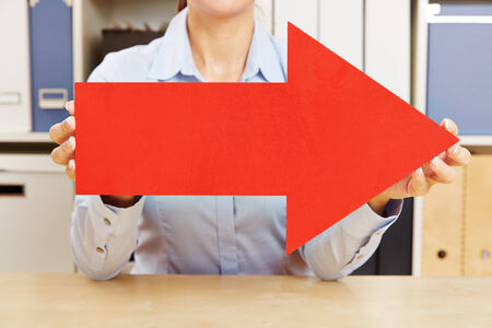 Two hands holding a big red arrow to the rightの写真素材