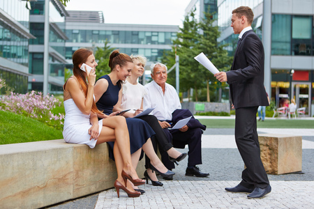 Business man giving presentation to team outdoors in summerの写真素材