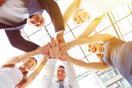 Happy group of businesspeople stacking their hands in cooperation