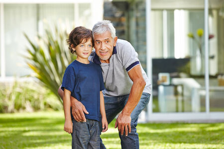 Happy grandfather talking with his grandchild in a summer garden