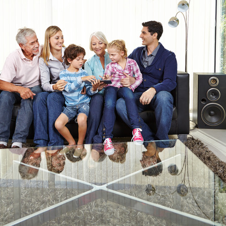 Two children playing with parents and grandparents with a tablet computer