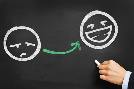 Hand drawing unhappy and happy smileys on blackboardの写真素材