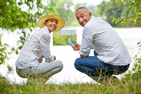 Senior people learning to paint in art class in nature on a lakeの写真素材