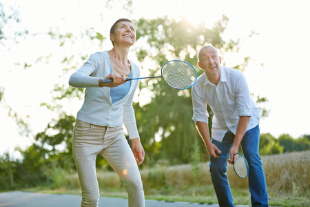 Senior couple playing badminton in summer in natureの写真素材