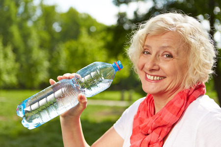 Smiling senior woman drinking fresh water in summerの写真素材