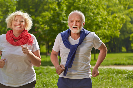 Two happy senior people jogging in a park in summerの写真素材