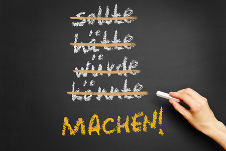 Hand writing motivational slogan in German (Do It) on a chalkboardの写真素材