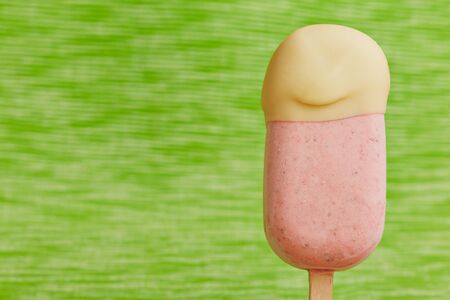 ice stick with strawberry ice cream and white chocolate in front of a green background