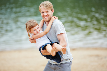 Father and daughter playing and romping on beach in summerの写真素材