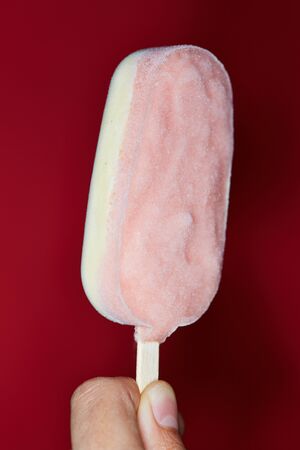 Hand holding ice cream popsicle with two flavorsの写真素材