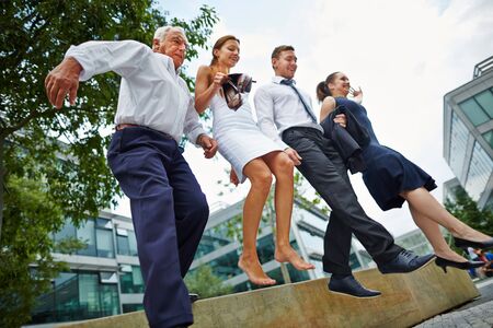 Group of business people jumping together over obstacle outdoorsの写真素材