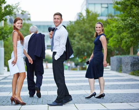 Smiling business people turning around while walking in the cityの写真素材