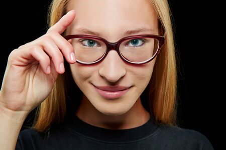 Smiling young blonde woman with her hand on her glasses
