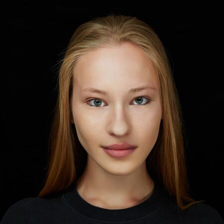 Face of a young attractive blonde woman in front view on dark backgroundの写真素材