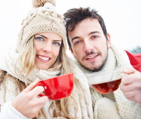 Woman and man drinking together cups of hot black tea in winterの写真素材