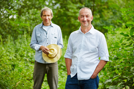 Two old men standing in summer in nature in a forestの写真素材