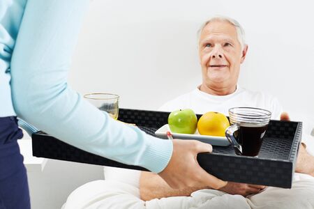 Old man eating breakfast in bed at homeの写真素材