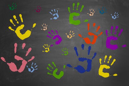 Many different colorful hand prints on a blackboardの写真素材