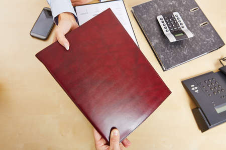 Hands holding a rÃ©sumÃ© from above on an office deskの写真素材