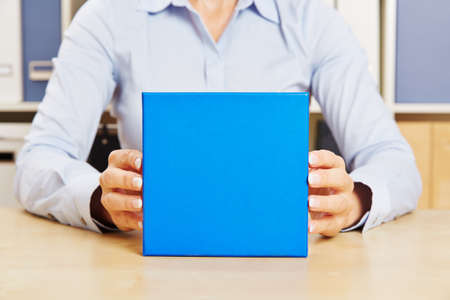 Hands of business man holding blue gift on office deskの写真素材