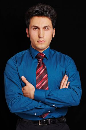 Serious looking businessman with his arms crossed on a black backgroundの写真素材