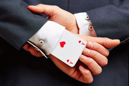 Business man with ace in his sleeve and arms on the backの写真素材