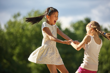Two happy girls dancing in a circle having fun in summerの写真素材