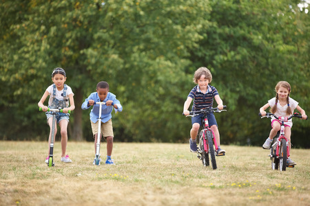 Children with mountainbike and scooter racing at the park