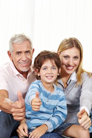 Happy family in living room holding thumbs up for congratulationsの写真素材