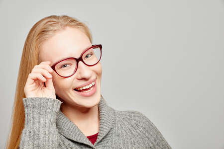 Young smiling beautiful woman with her hand on her glasses