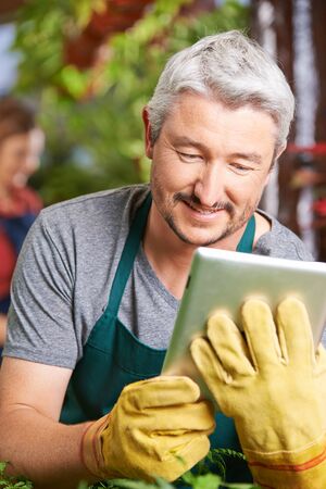 Gardener in a greenhouse buying new plants with a tablet computerの写真素材
