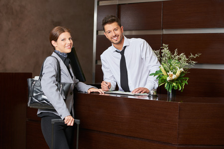 Woman during check-in at hotel reception with receptionistの写真素材