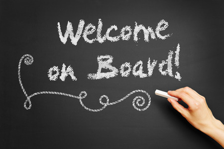 Hand writes "Welcome on board!" on blackboardの写真素材